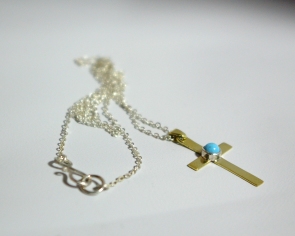 A cross pendant with turquoise set in sterling silver